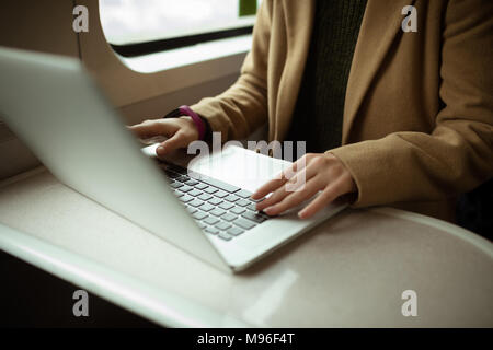 Capelli rossi giovane donna con il suo computer portatile in treno Foto Stock