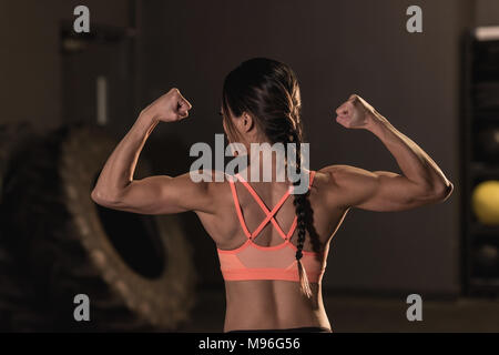 Vista posteriore di montare donna flettendo i suoi muscoli Foto Stock