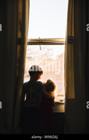 Bambini abbracciando accanto alla finestra dim spazio