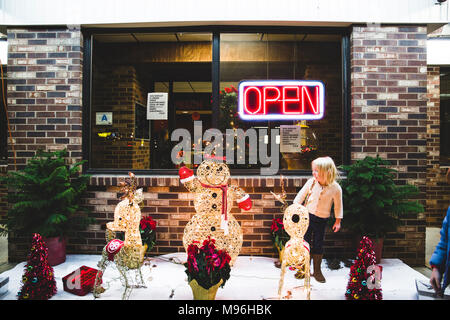 Ragazza con decorazioni di Natale accanto al ristorante aperto Foto Stock