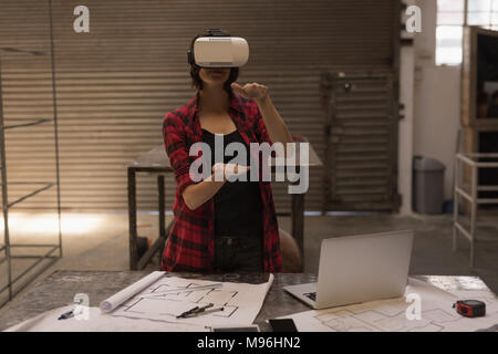 Saldatore femmina utilizzando la realtà virtuale auricolare Foto Stock