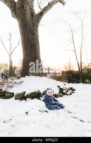 Ragazza seduta nella neve con giacca blu su Foto Stock