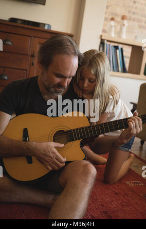 Padre con la figlia a suonare la chitarra in salotto Foto Stock