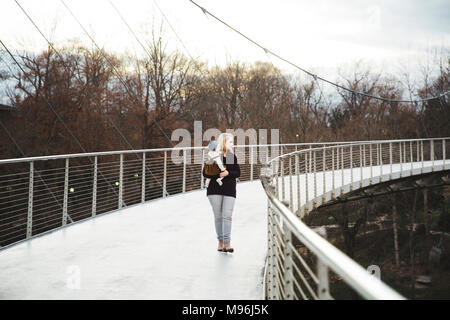 Donna che mantiene il bambino su un ponte metallico Foto Stock