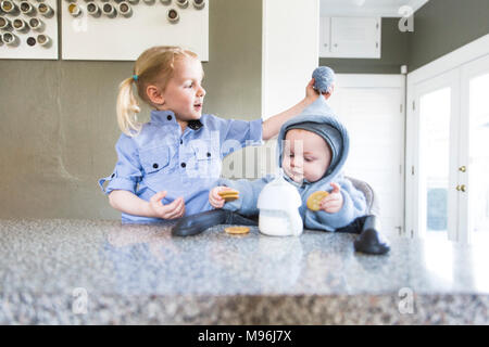 La ragazza e il bambino vestito di blu al banco di cucina Foto Stock