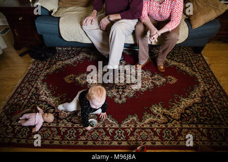 La famiglia sul lettino con baby doll e sul pavimento Foto Stock