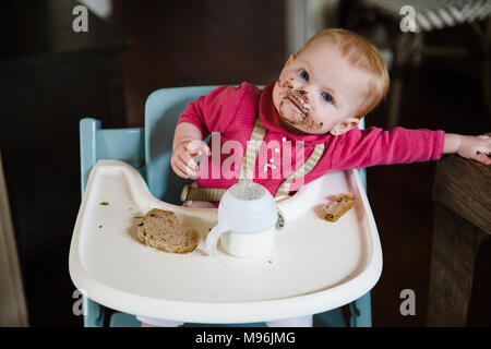 Baby in alta sedia con faccia disordinato mangiare pasti Foto Stock