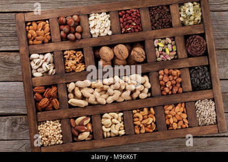 Vari dadi selezione: arachidi, nocciole, castagne, noci, pistacchi e le noci pecan in una scatola di legno. Vista superiore Foto Stock