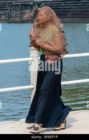 Una donna coveres la sua testa e braccia con un semi-trasparente foulard di seta per mantenere il sole fuori la sua pelle, la Cambogia. Foto Stock
