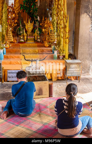 Due persone che pregano presso un altare all'interno del sito Patrimonio Mondiale dell'UNESCO di Angkor Wat, Siem Reap, Cambogia Foto Stock