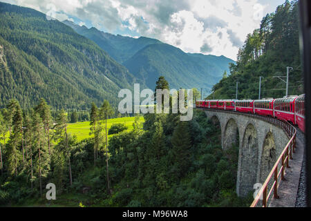 Bernina Express treno viaggia attraverso Alpi svizzere su viadotti Foto Stock