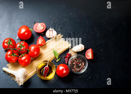 Il ramo mature materie pomodori aglio ed erbe su sfondo nero. Copia dello spazio. Foto Stock