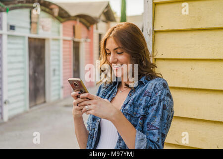 Ritratto di sorridente giovane donna tramite telefono cellulare Foto Stock