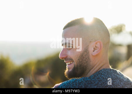 Profilo di felice giovane uomo in controluce Foto Stock