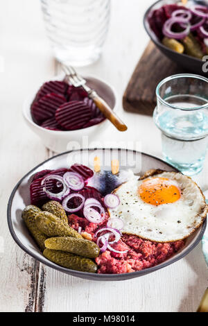 Labskaus, rollmops, cetriolino sottaceto, Insalata di barbabietole, cipolla e uovo fritto Foto Stock