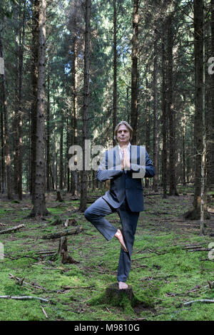 Imprenditore a praticare yoga in foresta Foto Stock