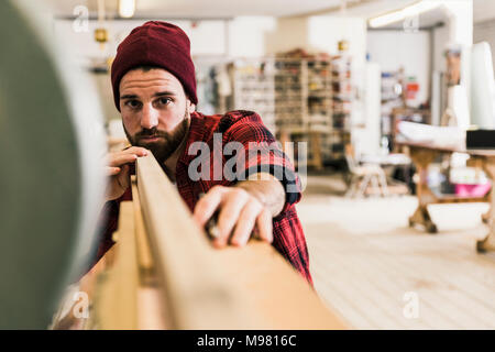 L'uomo esaminando il legno in officina Foto Stock