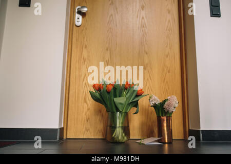 Addio fiori, candele e condolende card presso appartamento porta del defunto prossimo Foto Stock