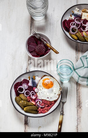 Labskaus, rollmops, cetriolino sottaceto, Insalata di barbabietole, cipolla e uovo fritto Foto Stock