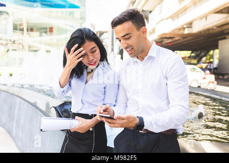 Thailandia, Bangkok, imprenditore e imprenditrice nella città con un telefono cellulare Foto Stock