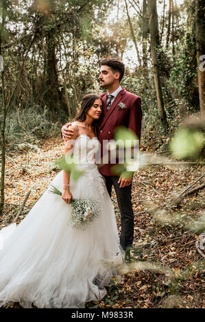 Lo sposo abbracciando sposa con gli occhi chiusi nella foresta Foto Stock