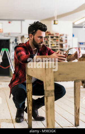 L'uomo il trattamento del legno in officina con della carta vetrata Foto Stock