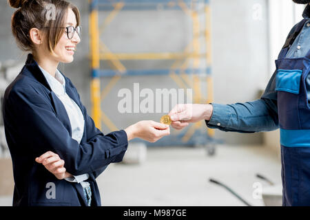 Donna cryptocurrency dando ad un builder Foto Stock