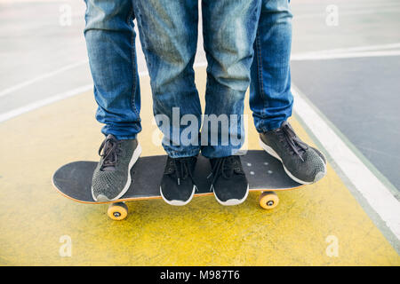 Gambe di adulto e bambino su skateboard Foto Stock