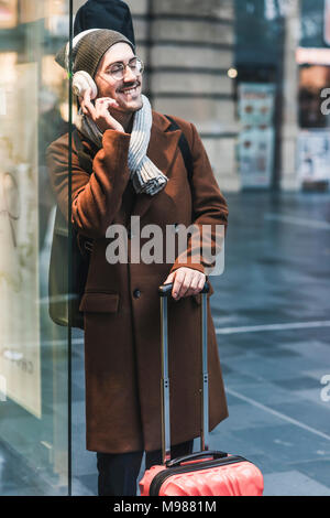 Sorridente giovane con chitarra caso presso la stazione di ascolto di musica Foto Stock