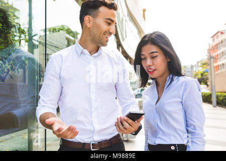 Thailandia, Bangkok, imprenditore e imprenditrice nella città con un telefono cellulare Foto Stock