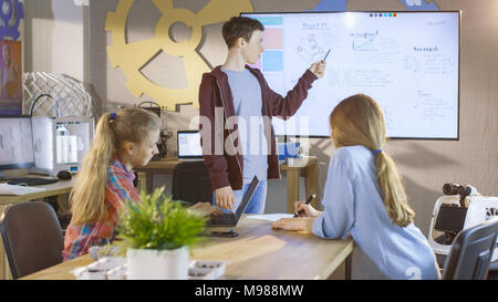 Ragazzo mostra la sua presentazione su lavagna interattiva Progetto per imminente la scienza a scuola di classe. Foto Stock