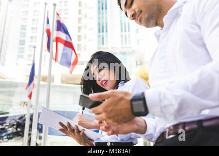 Thailandia, Bangkok, imprenditore e imprenditrice nella città con documenti, cellulare e smartwatch Foto Stock