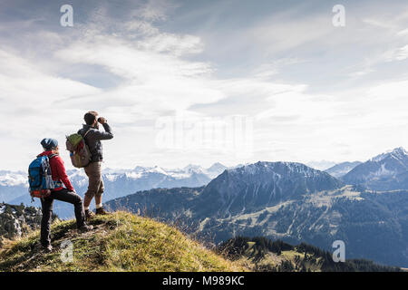 Austria, Tirolo, coppia giovane in piedi in mountainscape guardando a vista Foto Stock