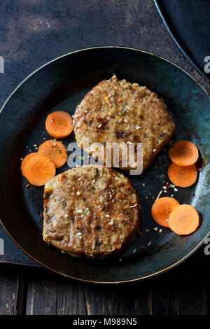 Hamburger Vegetariano e fette di carota in padella Foto Stock