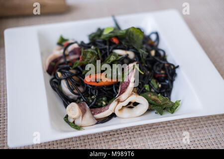 Frutti di mare piccante inchiostro nero spaghetti servita su piastra bianca Foto Stock