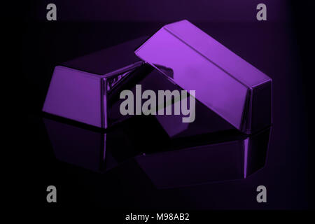 Gold bullion bars su uno sfondo nero nella luce viola Foto Stock