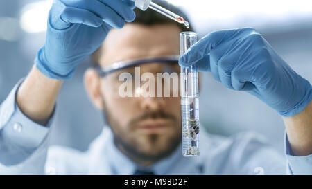 In un moderno laboratorio di uno scienziato conduce esperimenti mediante gocciolamento in una provetta con impianto modificato. Foto Stock