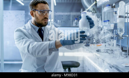 In una ricerca Chimica laboratorio di uno scienziato trattiene il fumo composto nel bicchiere. Foto Stock