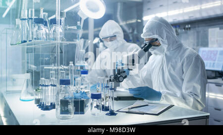 In un luogo sicuro ad alto livello gli scienziati del laboratorio in una tuta da lavoro a condurre una ricerca. Farmacia regola i campioni in piastre Petri con pinze e poi Examins Foto Stock