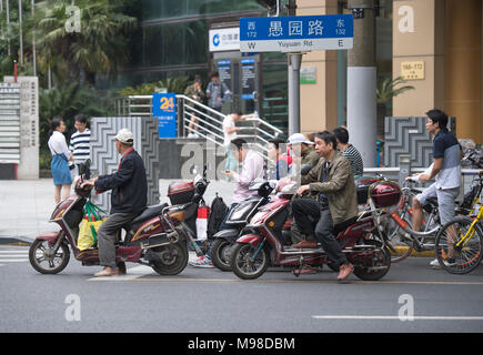 Persone a cavallo delle biciclette e scooter sulle strade di Shanghai in Cina Foto Stock