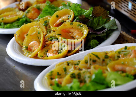 Vietnamese street food, frittelle di colore giallo sulla piastra cucina a fiera a Ho Chi Minh City, Vietnam, torte fare da farina di riso, gamberi freschi, beansprouts Foto Stock