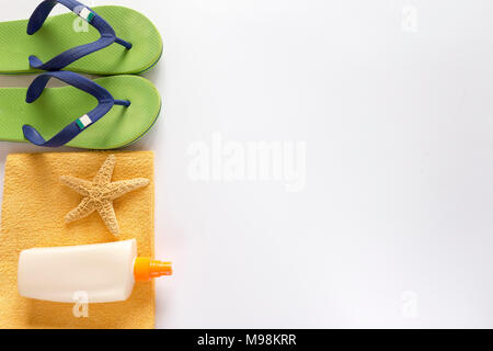 Mare pantofole, protezione solare e asciugamani su sfondo bianco Foto Stock
