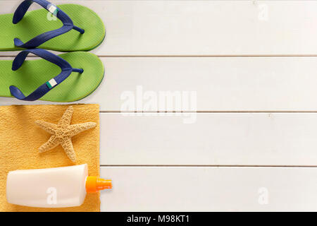 Mare pantofole, protezione solare e asciugamani su sfondo di legno Foto Stock