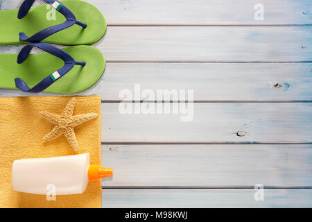 Mare pantofole, protezione solare e asciugamani su sfondo di legno Foto Stock