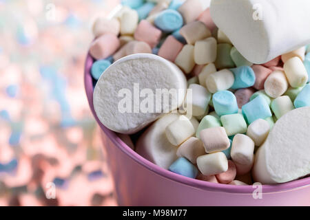 Violetta secchio con vari marshmallows su uno sfondo di colore rosa. Foto Stock