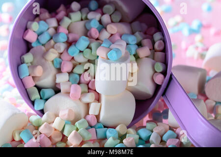 Violetta secchio con vari marshmallows su uno sfondo di colore rosa. Foto Stock