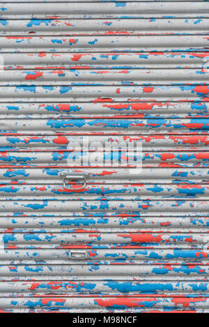 Martoriato di rullo di chiusura sportello con peeling vernice. Metafora chiusa per business, high street crisi, vacante negozi. La vecchia vernice texture, ostruita. Foto Stock