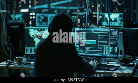 Hacker adolescenti che lavora con il suo computer di infettare i server e infrastruttura con malware. Il suo nascondiglio è scuro, illuminati al neon e ha più display. Foto Stock