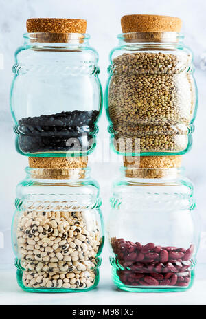 Diversi tipi di legumi in vasi di vetro con coperchi di sughero su un Sfondo marmo Foto Stock