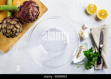 Ampio recipiente di vetro per la pulizia e la cottura di carni grande Carciofo romanesco verde-viola le teste dei fiori pronto per cuocere cibi stagionali Foto Stock